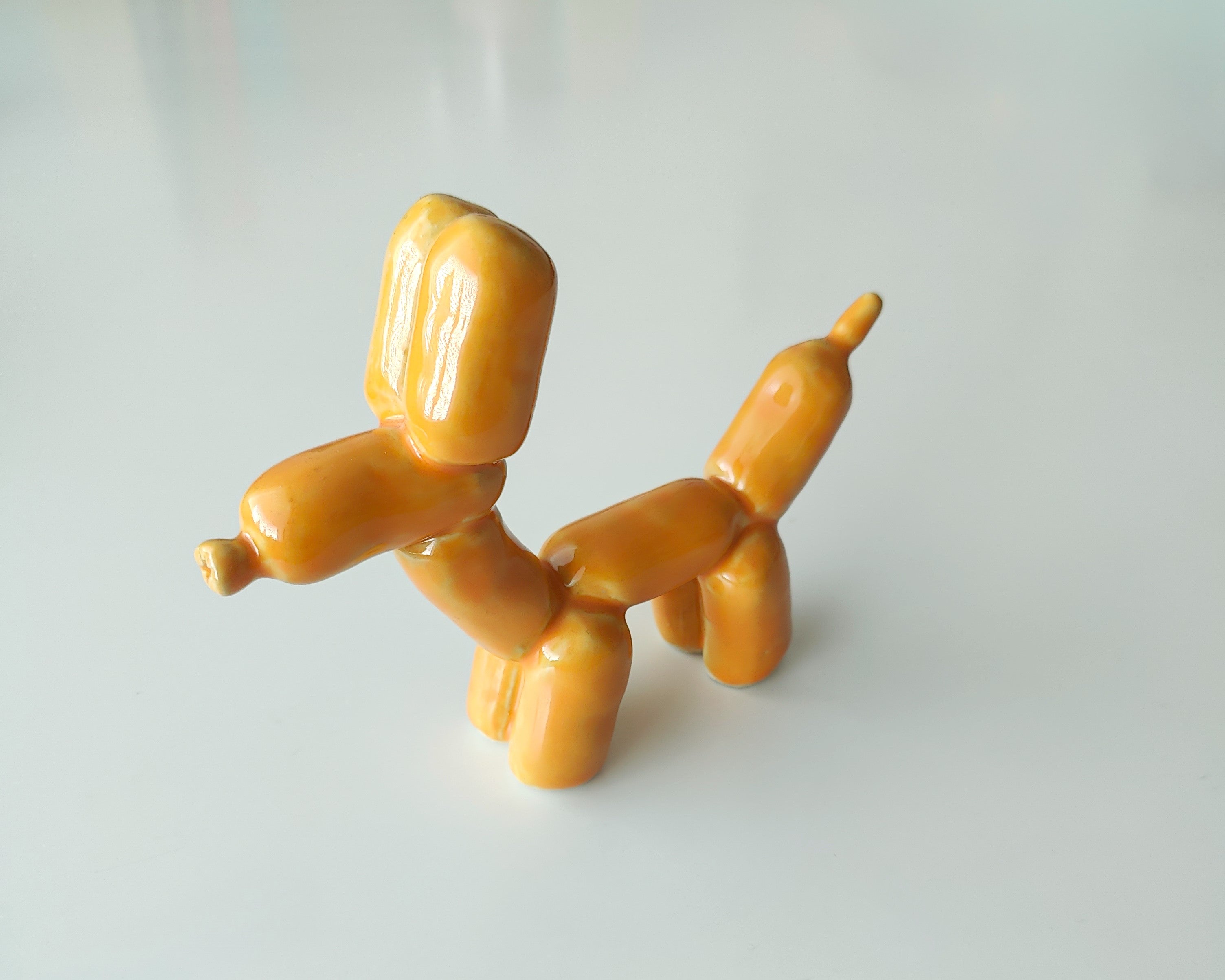 Keraaminen veistos oranssisesta ilmapallokoirasta.